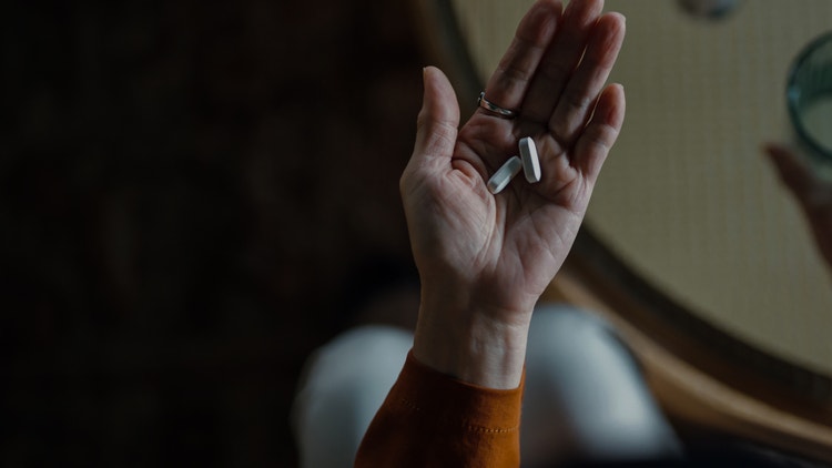 Hand holding two white capsules